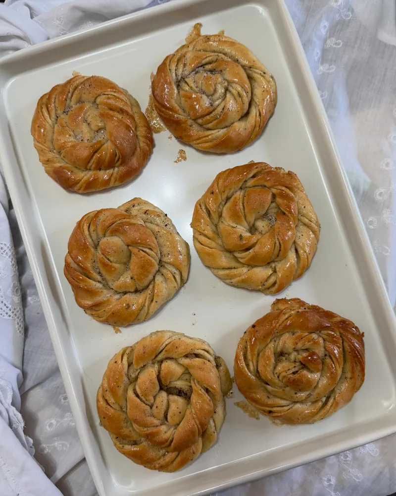 Six Swedish cardamom buns, knotted by hand, on a tray