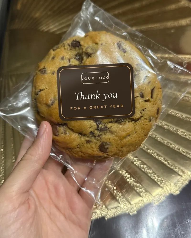 A wrapped cookie with a dark sticker reading Thank you for a great year, with space for a company logo