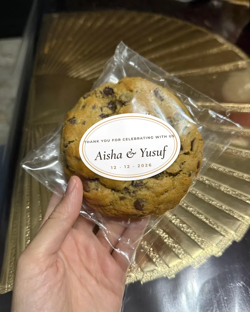 A wrapped cookie with an oval wedding sticker reading Aisha and Yusuf