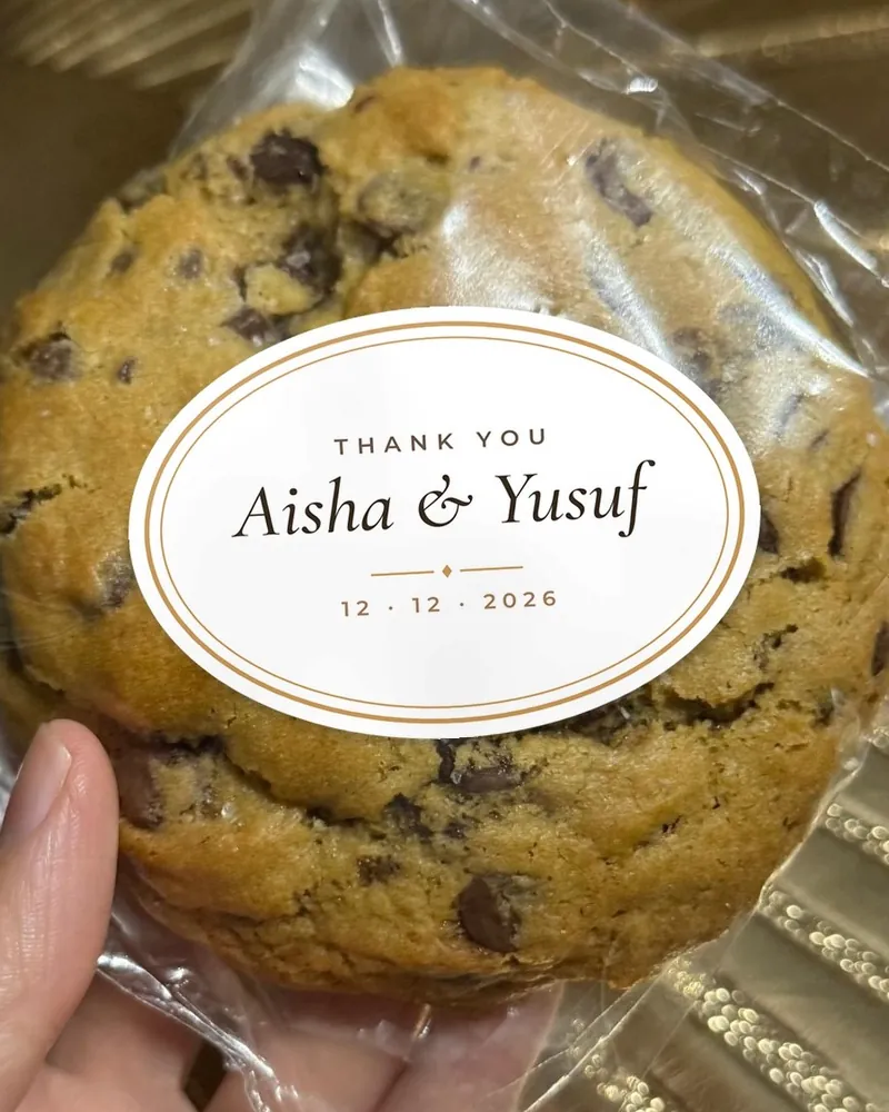 A wrapped cookie with an oval wedding sticker reading Thank you, Aisha and Yusuf, 12 December 2026